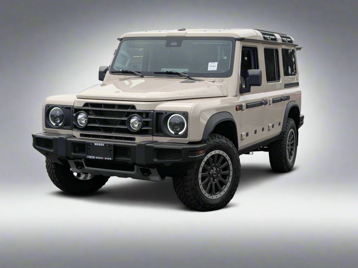 Beige Land Rover Defender in a parking lot with other vehicles.