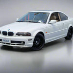 White BMW car parked in a lot with a building and fence in the background