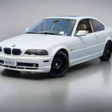 White BMW car parked in a lot with a building and fence in the background
